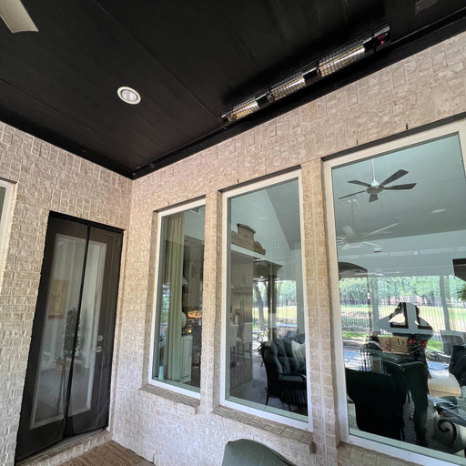 RADtec outdoor patio heaters mounted on a brick wall above a modern dining setup with chandelier near glass windows