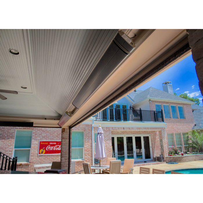 Mounted black patio heater on brick wall beneath “Gather” sign and vintage clock in covered outdoor space