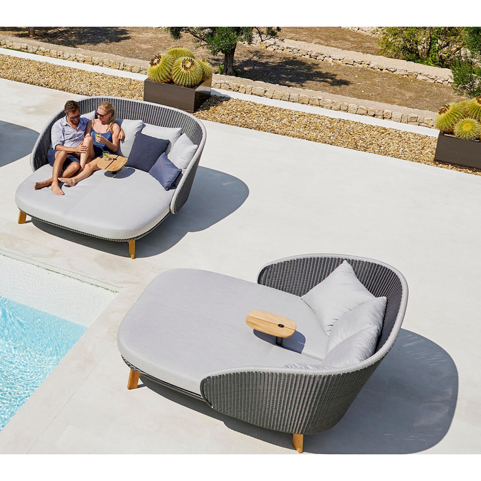 cane-line peacock daybed without parasol in a pool with 2 people enjoying the daybed