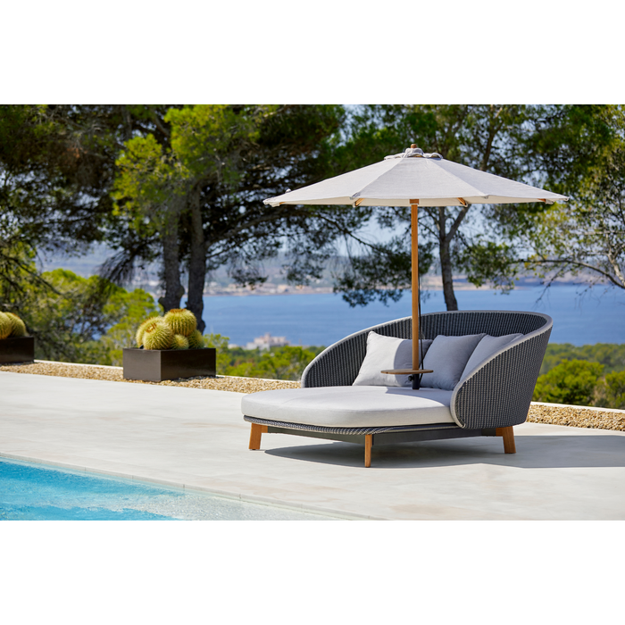cane-line peacock daybed with parasol in a pool lifestyle