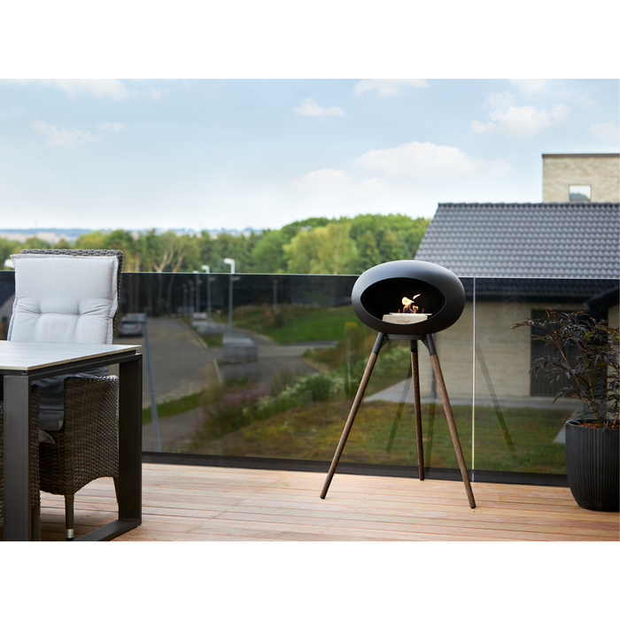 Le Feu Black Dome Bioethanol Fireplace ground high black bowl, smoked legs and steel burner in a patio with outdoor furniture lifestyle