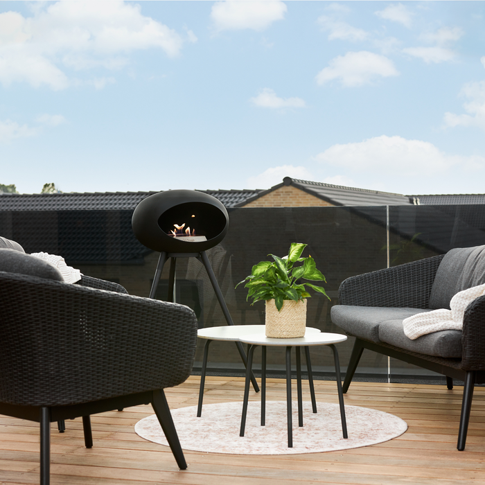 Le Feu Black Dome Bioethanol Fireplace ground high black bowl, black legs and rose gold burner in a patio with outdoor furniture lifestyle