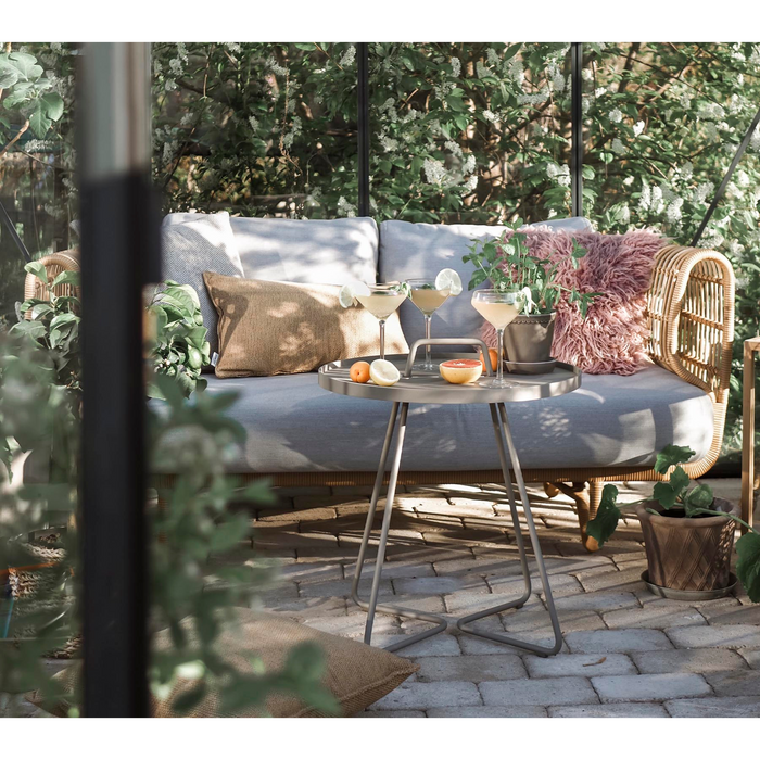 Nest outdoor 2 seater Sofa Light Grey Natte cushion in a patio with round table lifestyle