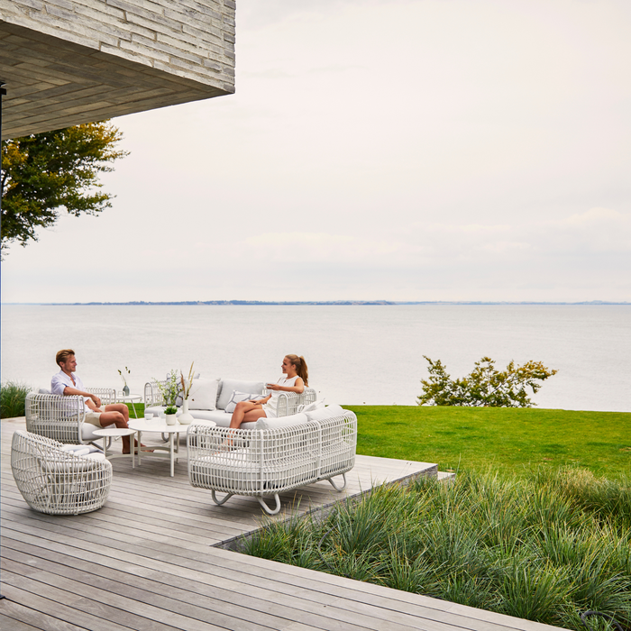 Nest outdoor 2 seater Sofa Light Grey Natte cushion in a garden with 2 persons enjoying the furniture lifestyle
