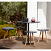 lifestyle image of cane-line area table stool in Teak w/Lava Grey Aluminium in a patio with dining table