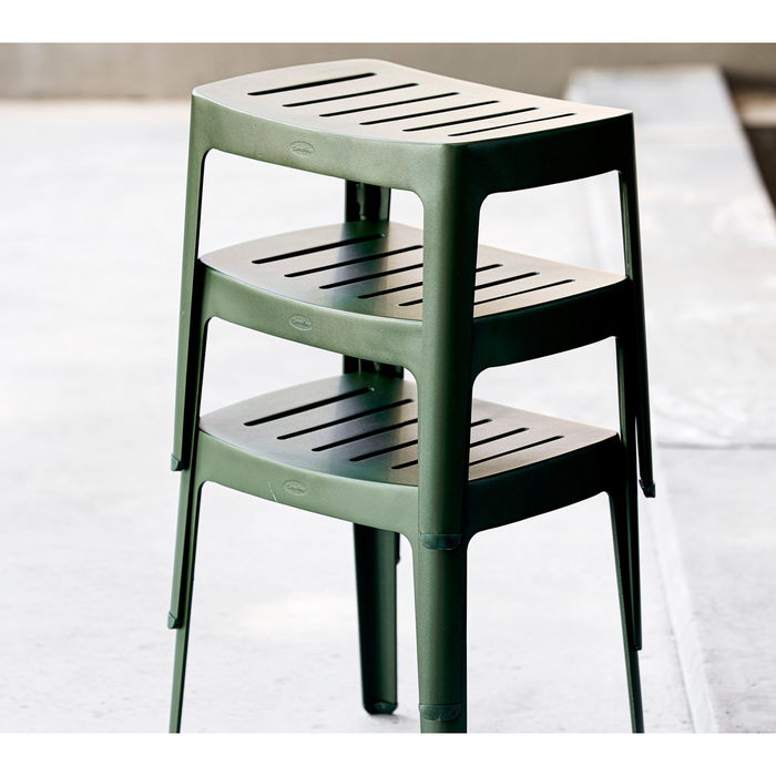 lifestyle image of cane-line cut stool in Dark Green, Aluminium chair without cushion stacked in a patio