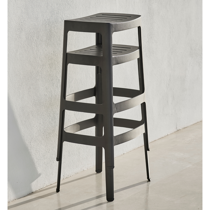 lifestyle image of cane-line cut stool in Black, Aluminium chair without cushion stacked in a patio