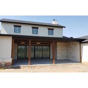 Modern house exterior with large glass door  with mounted Rad tec heaters and beige walls under clear blue sky
