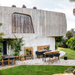 lifestyle image of cane-line drop greenhouse in Teak w/Lava Grey Aluminium in a garden with plants inside and outdoor furniture