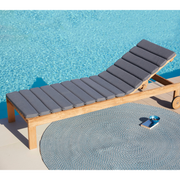 cane-line amaze sunbed teak sunbed with grey, cane-line natté cushion leaning forward with carpet in a pool lifestyle