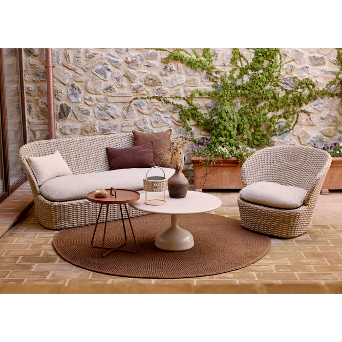 lifestyle image of cane-line glaze coffee table in large size with Sand, Semi Glossy Aluminium and Sand, Lava Stone Glazed table top in a patio with outdoor furniture