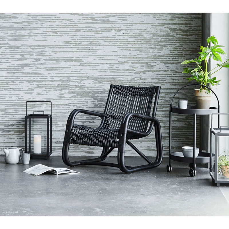 lifestyle image of cane-line roll trolley in black in a lounge with indoor chair