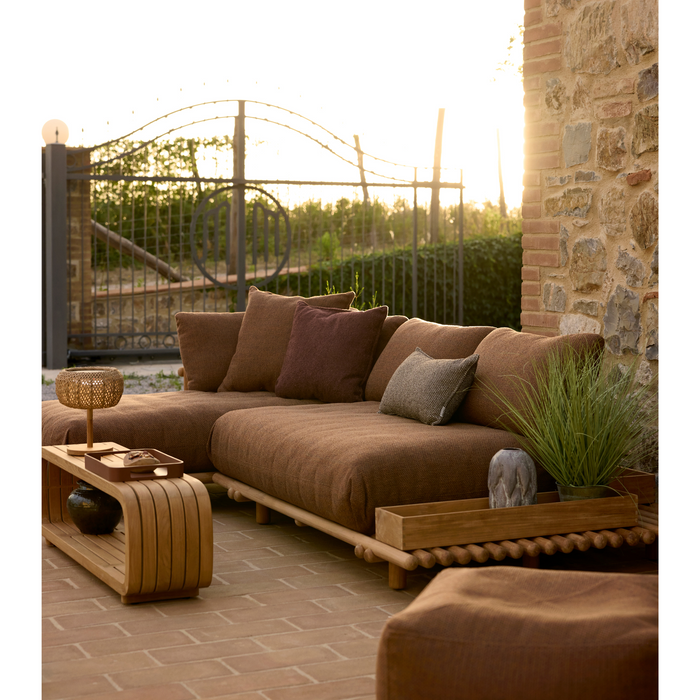 lifestyle image of cane-line rise scatter cushion 12" x 20" in Light Brown, Cane-line Rise and 19" x 19" in Umber Brown, Cane-line Rise on a sticks platform sofa in a patio with outdoor furniture