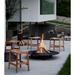 lifestyle image of cane-line flip stool in teak in a patio around a fire pit