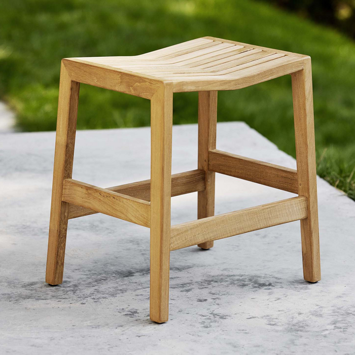 lifestyle image of cane-line flip stool in teak in a garden