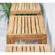 lifestyle image of cane-line flip bar chair in teak in a patio close up