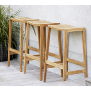 lifestyle image of cane-line flip bar chair in teak in a patio