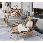 cane-line flip deck chair teak chair with Dark grey, Cane-line Focus cushion in a patio with two people enjoying the chair lifestyle 