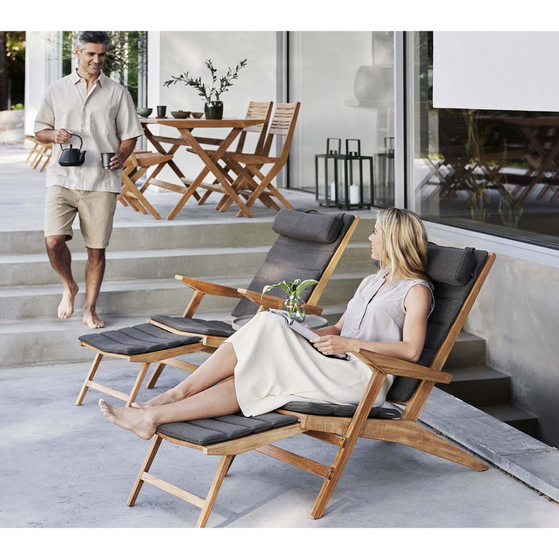 cane-line flip deck chair teak chair with Dark grey, Cane-line Focus cushion in a patio with two people enjoying the chair lifestyle 