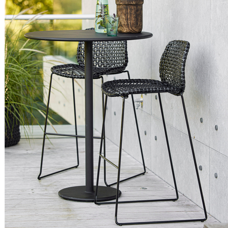 lifestyle image of cane-line vibe bar chair in Black/Graphite, Small Cross Cane-line Weave in a patio with bar table