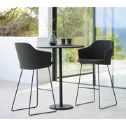lifestyle image of cane-line choice bar chair in Black, Polypropylene, Up to 98% Recycled chair, Black, Galvanized Steel w/4Legs base and Black, Cane-line Natté cushion with bar table in a patio