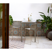 lifestyle image of cane-line breeze bar chair in Taupe, Small Round Cane-line Weave with high table in a patio