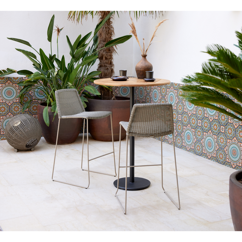 lifestyle image of cane-line breeze bar chair in Taupe, Small Round Cane-line Weave with bar table in a patio