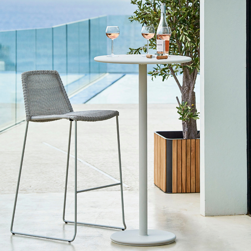 lifestyle image of cane-line breeze bar chair in White Grey, Small Round Cane-line Weave with bar table in a patio