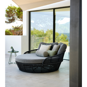 lifestyle image of cane-line ocean large daybed in Dark Grey, Open Cane-line Soft Rope daybed with Light Brown, Cane-line Wove cushion with outdoor cushions in a patio