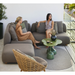 cane-line capture 2 seater sofa module taupe, cane-line airtouch sofa in a patio with outdoor furniture and women enjoying the sofa lifestyle