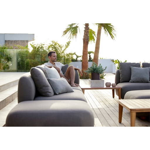 cane-line capture chaise lounge module sofa taupe, cane-line airtouch sofa in a patio with outdoor furniture and a man enjoying the sofa lifestyle