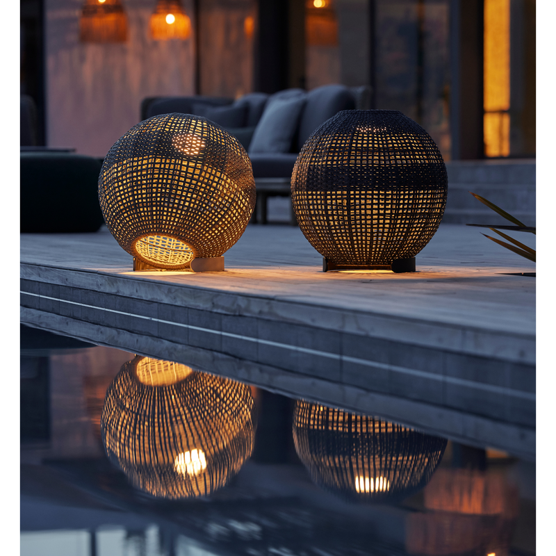 cane-line illusion lamp round taupe soft rope and dark grey soft rope lit in a patio with pool lifestyle