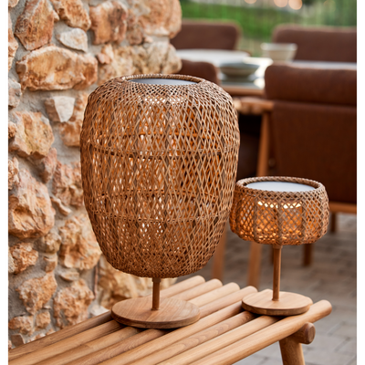 cane-line illusion glow table lamp medium and small natural with teak on a bench in a patio lifestyle