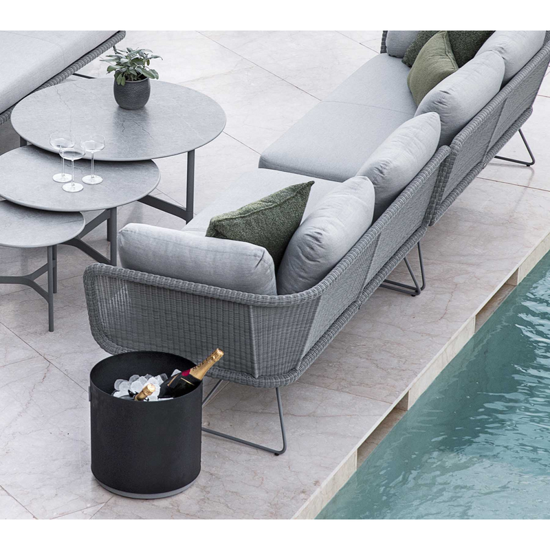 lifestyle image of cane-line grow planter small in Lava Grey/Light Grey, Aluminium with bottle in a patio with pool and outdoor furniture