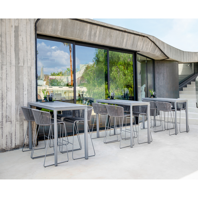 lifestyle image of cane-line moments bar chair in Grey, String Open Cane-line Soft Rope in a patio with bar table
