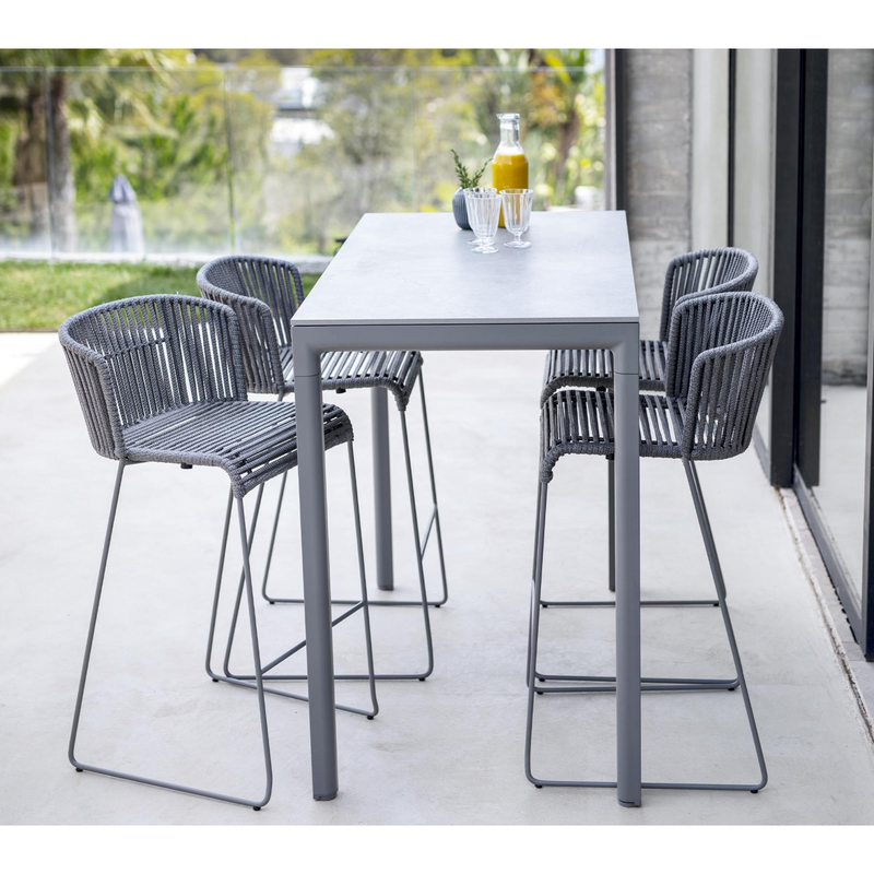 lifestyle image of cane-line moments bar chair in Grey, String Open Cane-line Soft Rope in a patio with bar table