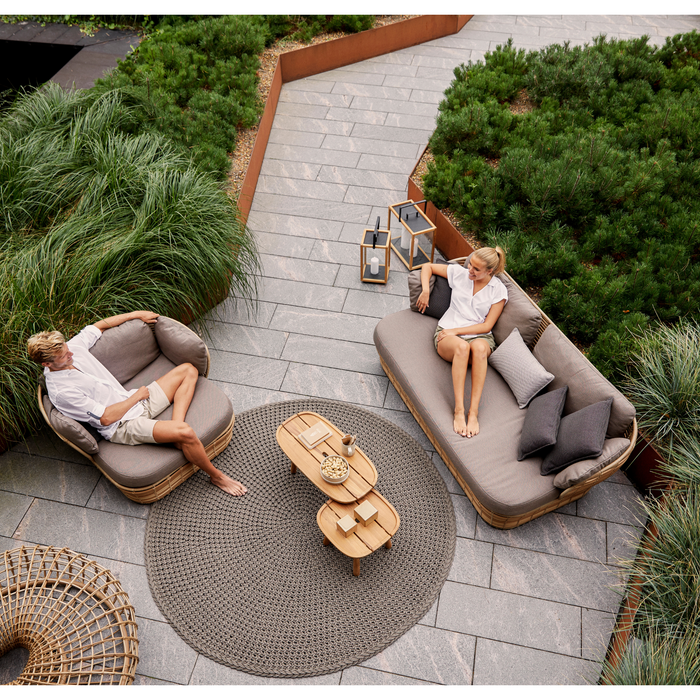 cane-line discover rug 78 taupe soft rope in a patio with outdoor furniture and two people enjoying the furniture lifestyle