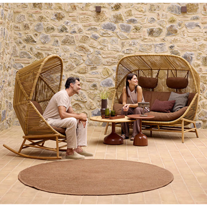 cane-line knit rug 78 umber brown soft rope in a patio with outdoor furniture and two people enjoying the furniture lifestyle