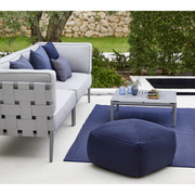 lifestyle image of cane-line divine footstool in Midnight Blue, Cane-line Divine in a patio with outdoor furniture