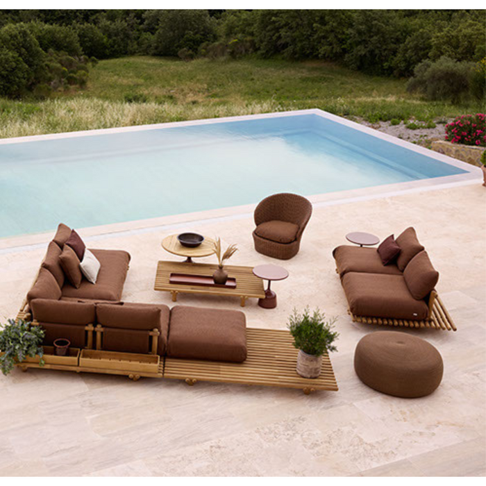 lifestyle image of cane-line circle footstool extra large in Umber Brown, Open Cane-line Soft Rope in a patio with pool and sticks furniture