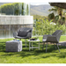 lifestyle image of cane-line cube footstool in Light Grey, Square Cane-line Soft Rope in a garden with outdoor furniture