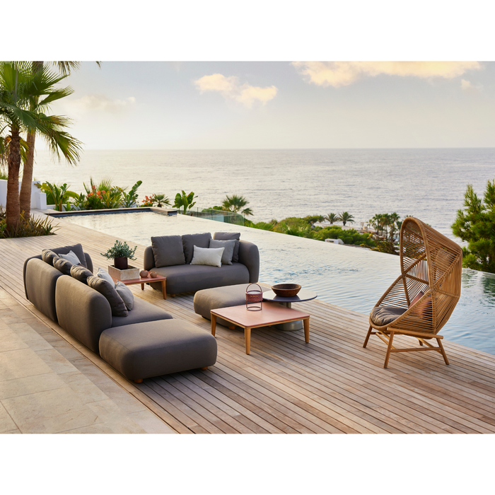 cane-line capture corner sofa with table, pouf & chaise lounge taupe, cane-line airtouch sofa in a patio with pool and hive chair lifestyle