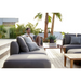 cane-line capture corner sofa with table, pouf & chaise lounge taupe, cane-line airtouch sofa in a patio with a man enjoying the sofa lifestyle