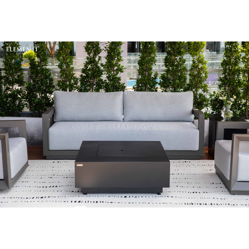 Elementi Newporrt collection Urbane Bronze Powder-Coated Frame w/ Granite Cushions Outdoor patio set , and fire pit table on a patio with plants and building in the background.