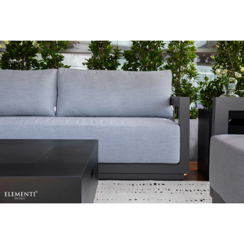 Elementi Newporrt collection Urbane Bronze Powder-Coated Frame w/ Granite Cushions outdoor sofa set with matching coffee table on a patio with greenery in the background.