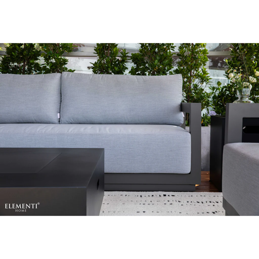 Elementi Newporrt collection Urbane Bronze Powder-Coated Frame w/ Granite Cushions outdoor sofa set with matching coffee table on a patio with greenery in the background.
