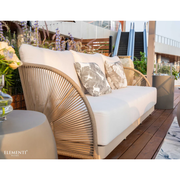Wicker and aluminum outdoor Elementi Malibu 3 seater sofa with white cushions on a wooden deck, featuring the Elementi brand.