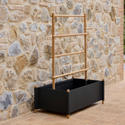 lifestyle image of cane-line sticks planter rack with planter in Teak w/Lava Grey Aluminium in a patio
