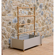 lifestyle image of cane-line sticks planter rack with planter in Teak w/Sand Aluminium in a patio