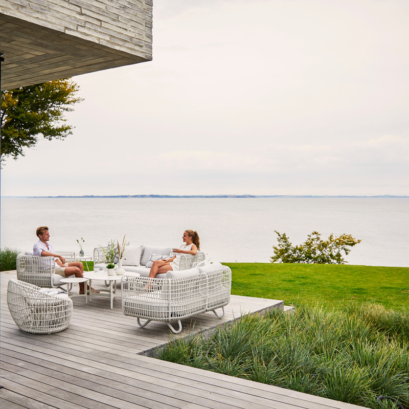 Nest outdoor 2 seater Sofa Light Grey Natte cushion in a garden with 2 persons enjoying the furniture lifestyle